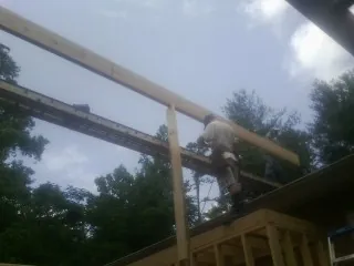 Carpenter setting a ridge beam over a new addition frame — Ice Dam Removal by Roofing Brothers in Odenville