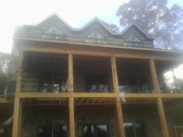 Dormers and porch framing on a large log home under construction — Roof Coating work by our crew in Odenville