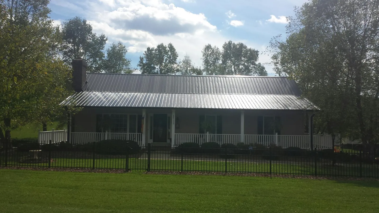 Gray metal roof on a brick ranch with a full width front porch — Gutter Guard Installation work by our crew in Odenville