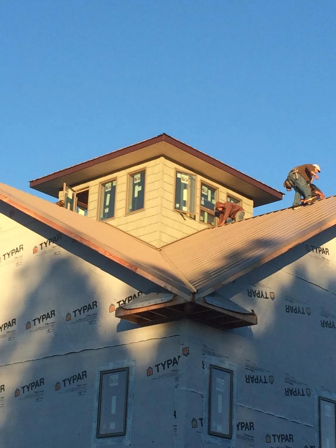 Roofers working around a rooftop cupola on a new metal roof at sunset — Roof Waterproofing in Odenville by Roofing Brothers